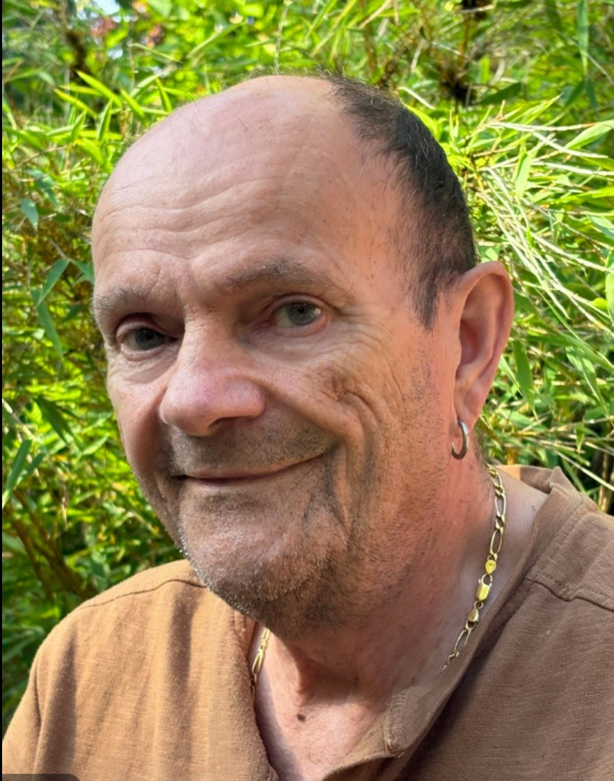 Portrait de Jean-Luc Bruegger souriant devant des feuillages verts