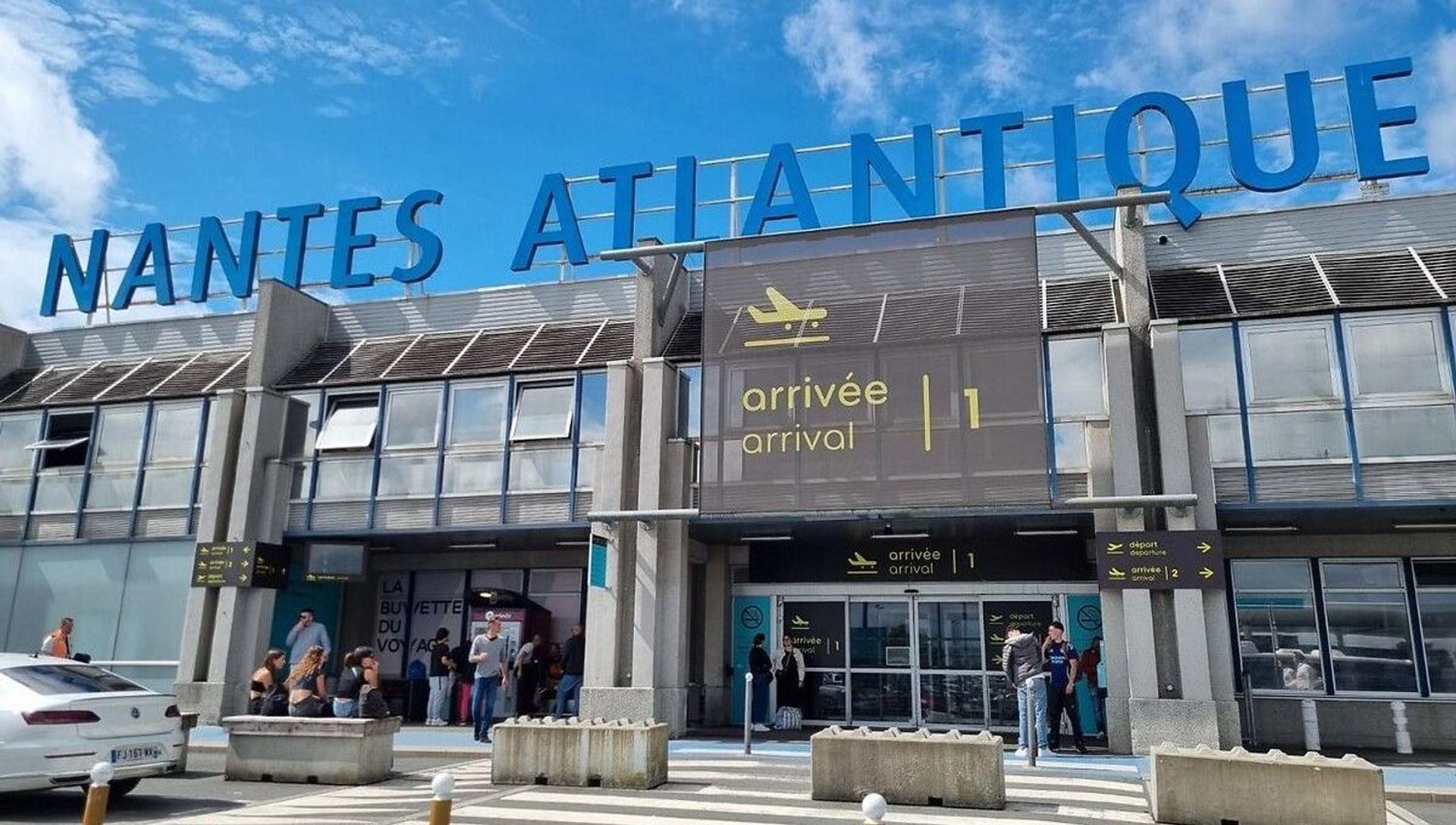 Terminal arrivées de l'aéroport Nantes Atlantique avec panneau et voyageurs